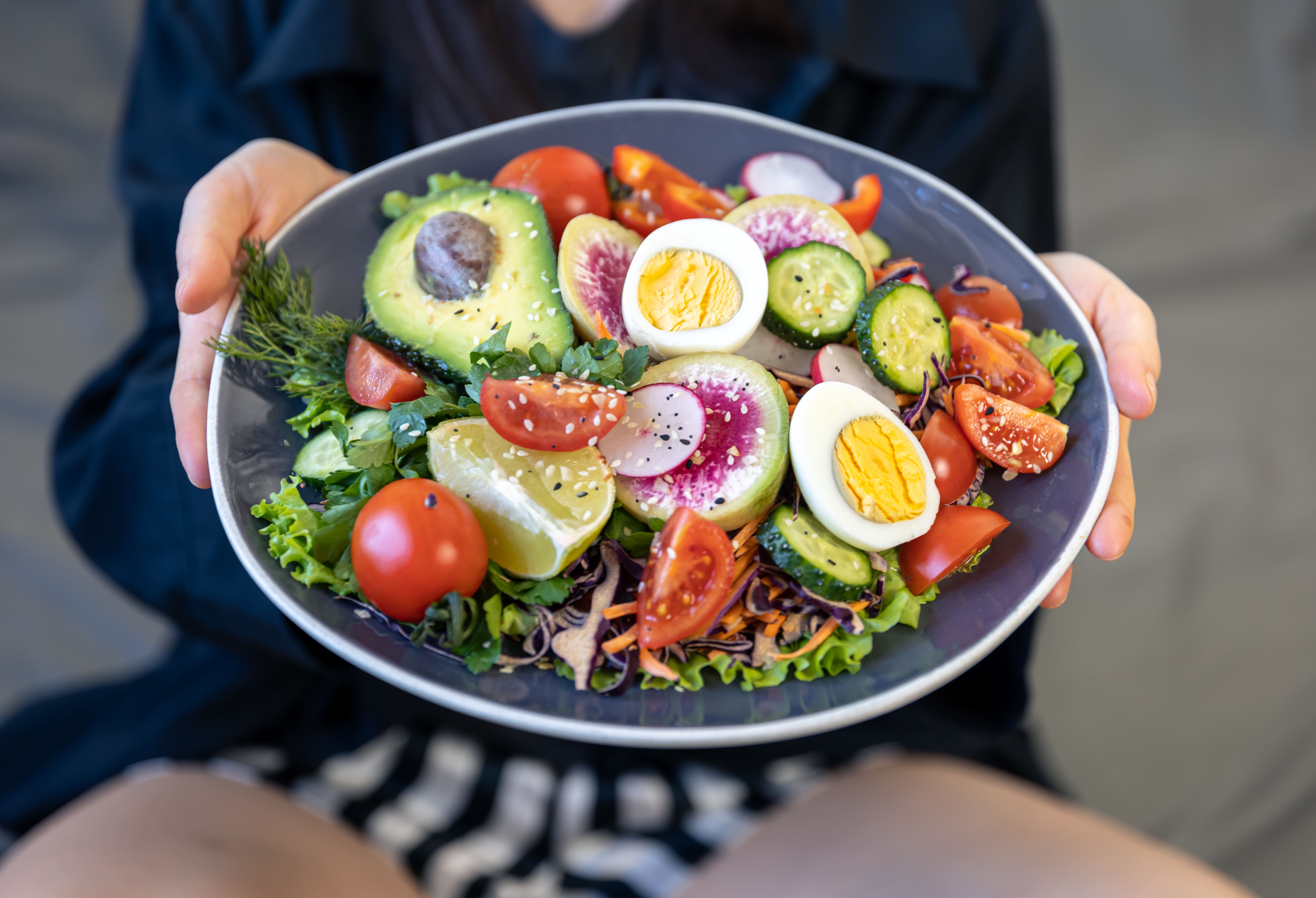 appetizing salad with fresh vegetables and eggs in a plate in female hands.
